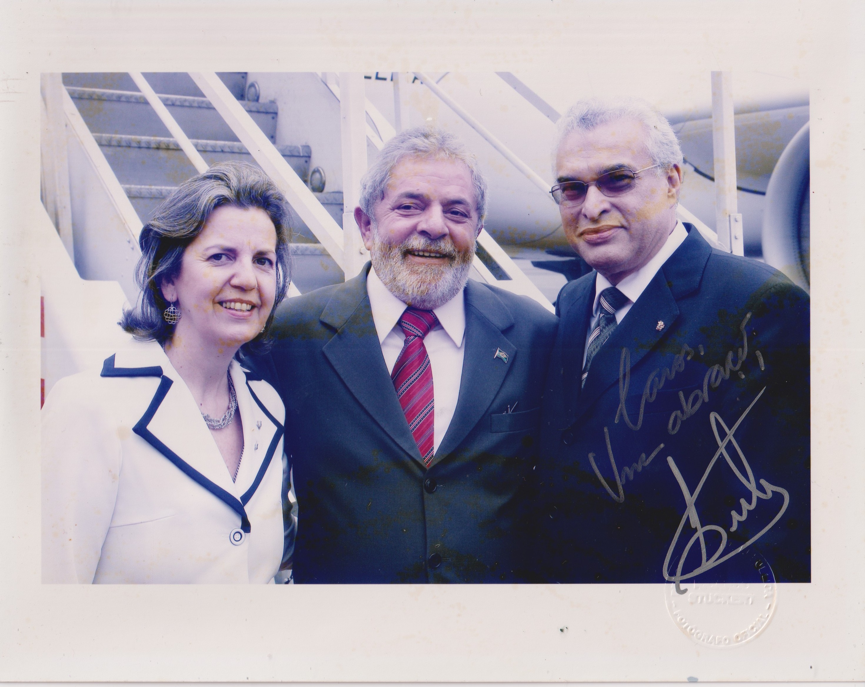 O embaixador Tadeu Valadares e a oficial de chancelaria Magali Valadares - esposa de Tadeu - recepcionam e posam para foto ao lado do presidente da República Luiz Inácio Lula da Silva, que estava em visita oficial a São José, na Costa Rica. Na foto, é possível ver a dedicatória assinada por Lula ao casal.